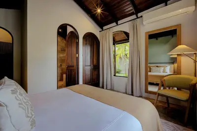 a bedroom with a white bed and a room with a bed sqor at The Garden Casitas by Vista Celestial in Uvita
