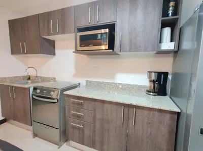 a kitchen with wooden cabinets and a microwave at Condo en Jacó in Jacó