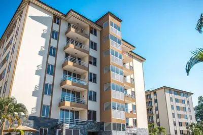 a tall building with palm trees in front of it at Condo en Jacó in Jacó