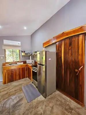 a kitchen with a stainless steel refrigerator and wooden cabinets at Casa Cariad Close to surfing lessons and more! in Parrita