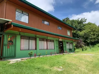 a green and brown house with a grass yard at Globi Lodge #5 in Monteverde Costa Rica
