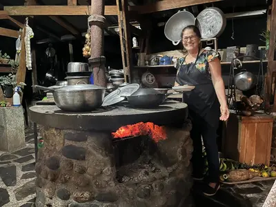 a woman standing in front of a stone oven at Botanica Gardens and Eco Lodge in San Gerardo