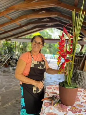 a woman standing next to a table with a potted plant at Botanica Gardens and Eco Lodge in San Gerardo