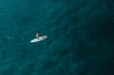 a person on a surfboard in the ocean at Spacious 2BR Condo with Ocean Glimpse - Jobo - Reserva Conchal Golf Resort in Playa Conchal