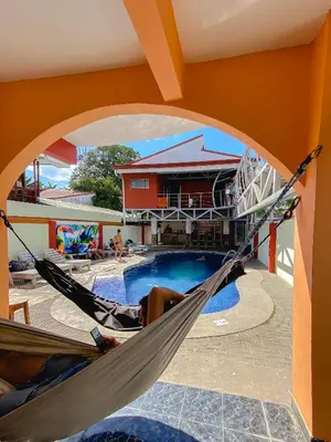a person laying in a hammock next to a pool at Hostel de Haan in Jacó