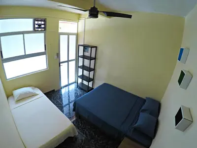 a small room with a bed and a window at Hostel de Haan in Jacó