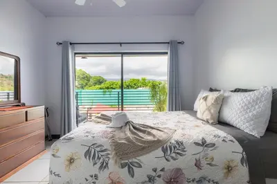 a bedroom with a bed and a large window at Private home with resort style swimming pool in Jacó