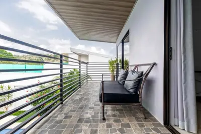 a balcony with a chair and a view of the ocean at Private home with resort style swimming pool in Jacó