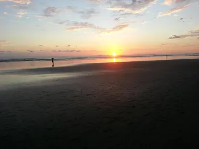 a person standing on the beach at sunset at Uvita Oasis Retreat with Villa Apt Bungalows Cabin in Uvita