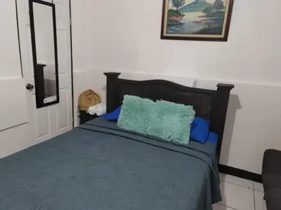 a bedroom with a bed with blue pillows at Gran Hotel Desamparados in Desamparados