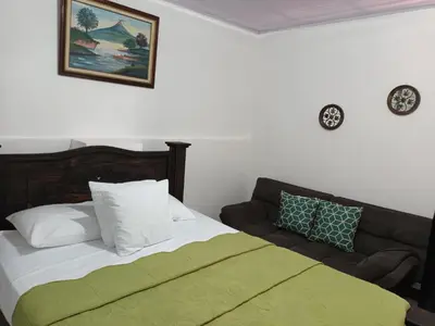 a bed with a green blanket next to a couch at Gran Hotel Desamparados in Desamparados