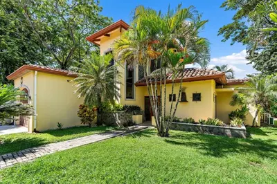 a yellow house with palm trees in the yard at Inviting Home with Colorful Decor and Private Backyard Oasis with a Swimming Pool & Shaded Terrace in Santa Cruz