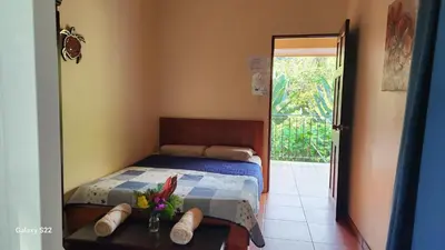 a bedroom with a bed and a table with flowers on it at YETHAN HOUSE in Uvita