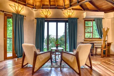 a living room with chairs and a table and a piano at Hotel Amor de Mar in Montezuma