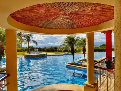 a swimming pool with an umbrella in a resort at CR MARIPOSA RENTALS Comfortable penthouse, AC, pool, gym, tennis in Santa Ana