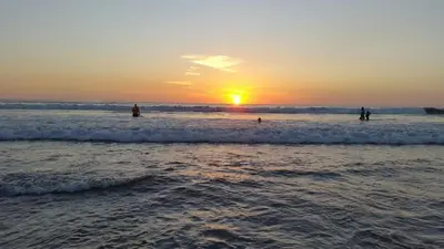 a group of people walking in the water at the beach at Hotel Hacienda Angeles in Paraíso