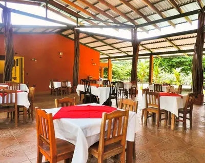 a restaurant with tables and chairs and a red and white table at Hotel Hacienda Angeles in Paraíso