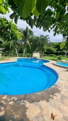 a large blue swimming pool with trees in the background at Hotel Hacienda Angeles in Paraíso