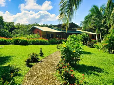 a house with a garden with flowers in front of it at Hotel Hacienda Angeles in Paraíso