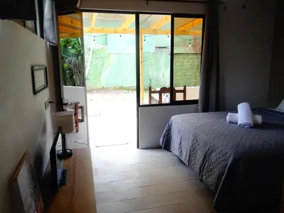 a bedroom with a bed and a sliding glass door at Airport Green Studio in Santiago Este
