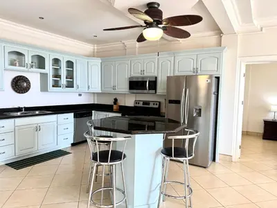 a kitchen with white cabinets and a stainless steel refrigerator at Seaside Serenity 2b2b with Panoramic Terrace in Coco