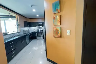 a kitchen with black cabinets and a yellow wall at Luxury beach condo, stunning sunset & ocean view in Jacó