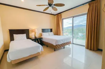a bedroom with two beds and a large window at Luxury beach condo, stunning sunset & ocean view in Jacó