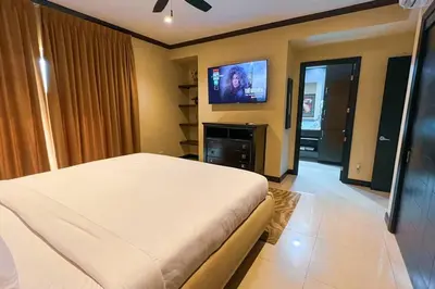 a bedroom with a bed and a flat screen tv at Luxury beach condo, stunning sunset & ocean view in Jacó