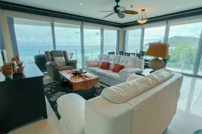 a living room with white furniture and a view of the ocean at Luxury beach condo, stunning sunset & ocean view in Jacó