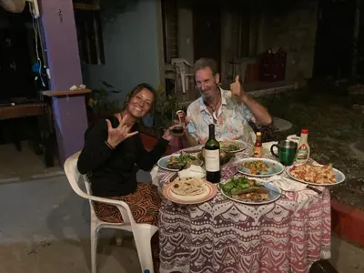 a man and a woman sitting at a table with food at Passiflora Backpackers Samara in Sámara