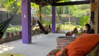 a couple of women sitting in hammocks in a porch at Passiflora Backpackers Samara in Sámara
