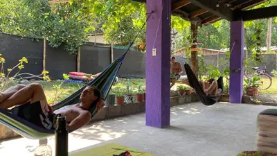 two men laying in hammocks in a garden at Passiflora Backpackers Samara in Sámara