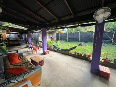 a patio with a couch and a hammock in a yard at Passiflora Backpackers Samara in Sámara