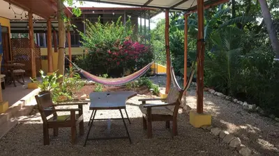 a hammock in a garden with chairs and a swing at Casa Flores Carrillo - Monkey Cabena in Carrillo