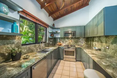 a kitchen with green cabinets and a counter top at Tropical Retreat - Private Pool, Steps to Beach in Tamarindo