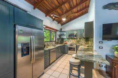 a kitchen with a stainless steel refrigerator and a counter at Tropical Retreat - Private Pool, Steps to Beach in Tamarindo