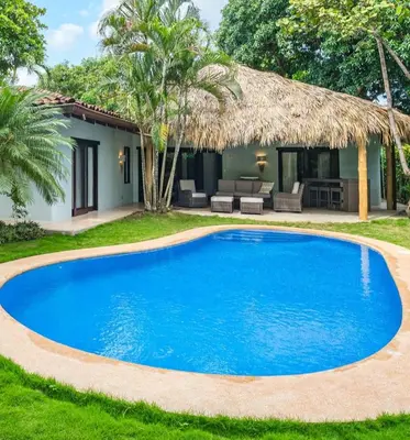 a blue swimming pool in front of a house at Tropical Retreat - Private Pool, Steps to Beach in Tamarindo