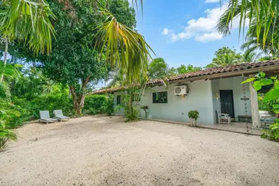 a white house with two chairs and a yard at Tropical Retreat - Private Pool, Steps to Beach in Tamarindo