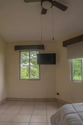 a bedroom with a ceiling fan and two windows at Organic Garden in San José