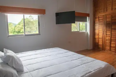 a bedroom with a white bed and a flat screen tv at Organic Garden in San José