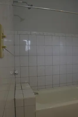 a white tiled bathroom with a tub and a window at Organic Garden in San José