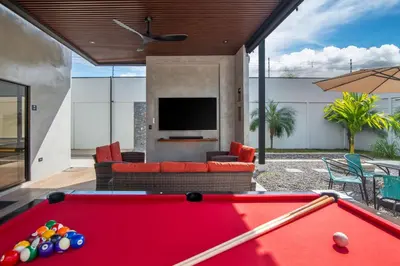 a pool table in a living room with a tv at La Casa de Papi. in Parrita