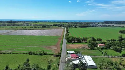 an aerial view of a farm with a road and fields at La Casa de Papi. in Parrita