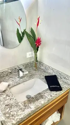 a bathroom sink with a vase of flowers and a book at Sharma Costa Rica- Mimosa Casita in Uvita