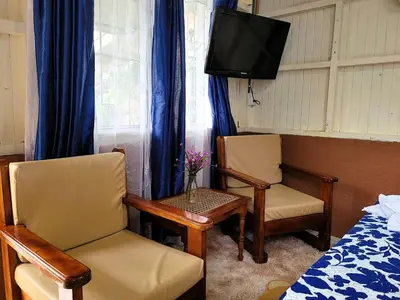 a room with two chairs and a tv and a bed at Tico Bed & Breakfast La Fortuna in Fortuna