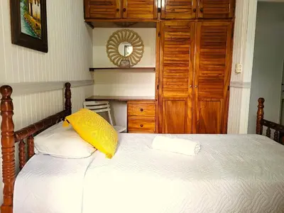 a bedroom with a bed with a yellow pillow on it at Tico Bed & Breakfast La Fortuna in Fortuna