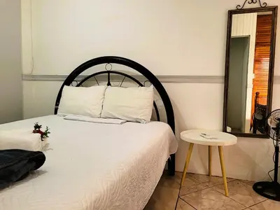 a bedroom with a bed and a mirror and a table at Tico Bed & Breakfast La Fortuna in Fortuna