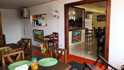 a dining room with tables and chairs and a kitchen at Tico Bed & Breakfast La Fortuna in Fortuna