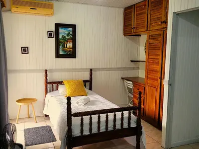 a bedroom with a bed with a yellow pillow on it at Tico Bed & Breakfast La Fortuna in Fortuna