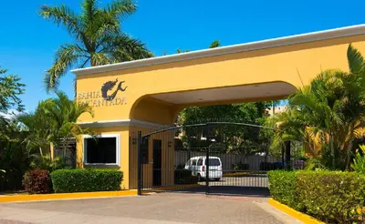 a yellow building with a gate in front of it at Apartamento de Lujo en Playa Jacó, Frente al Mar, Wifi, AC, Parqueo Privado y Piscinas in Jacó